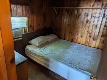 Master bedroom in The Cottage featuring a Queen bed and window air conditioning unit