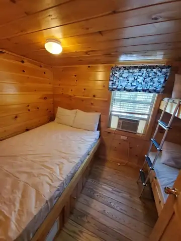 Deluxe Cabin bedroom featuring a Queen bed, twin bunk beds, and air conditioning