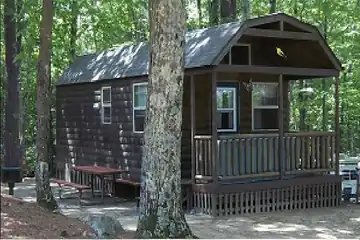 xterior view of a Deluxe Cabin rental featuring a covered porch and wooded setting