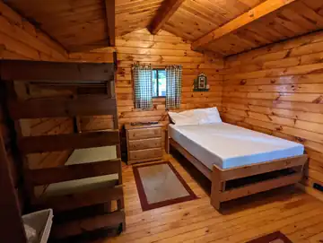 Rustic Cabin sleeping area featuring a double bed and sturdy wooden bunk beds